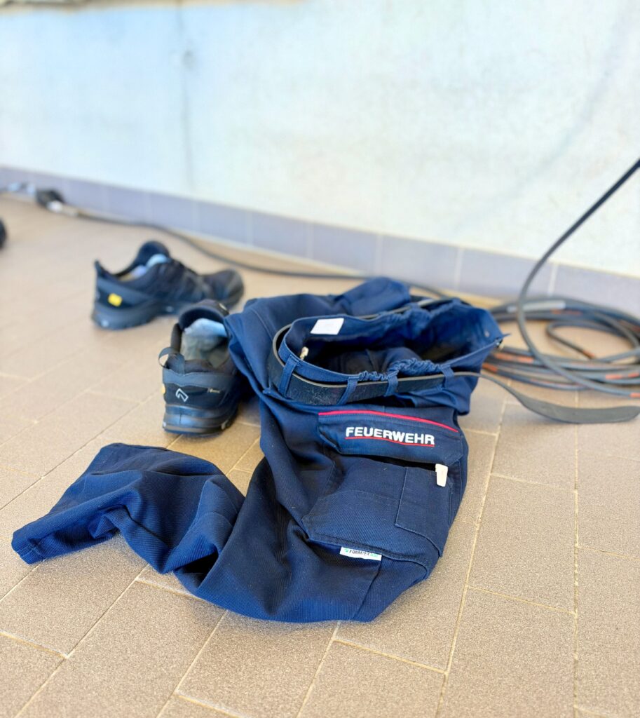 Die Hose eines Feuerwehrmannes liegt auf dem Boden, daneben seine Schuhe.